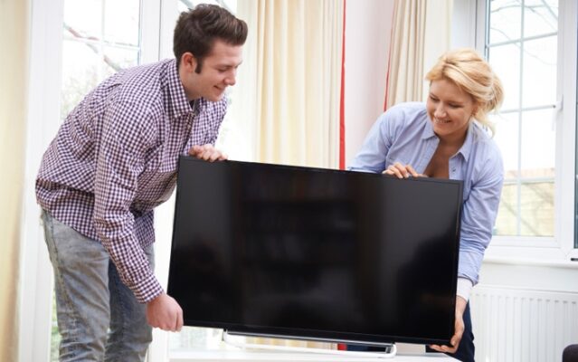 Excited Couple Setting Up New Television At Home